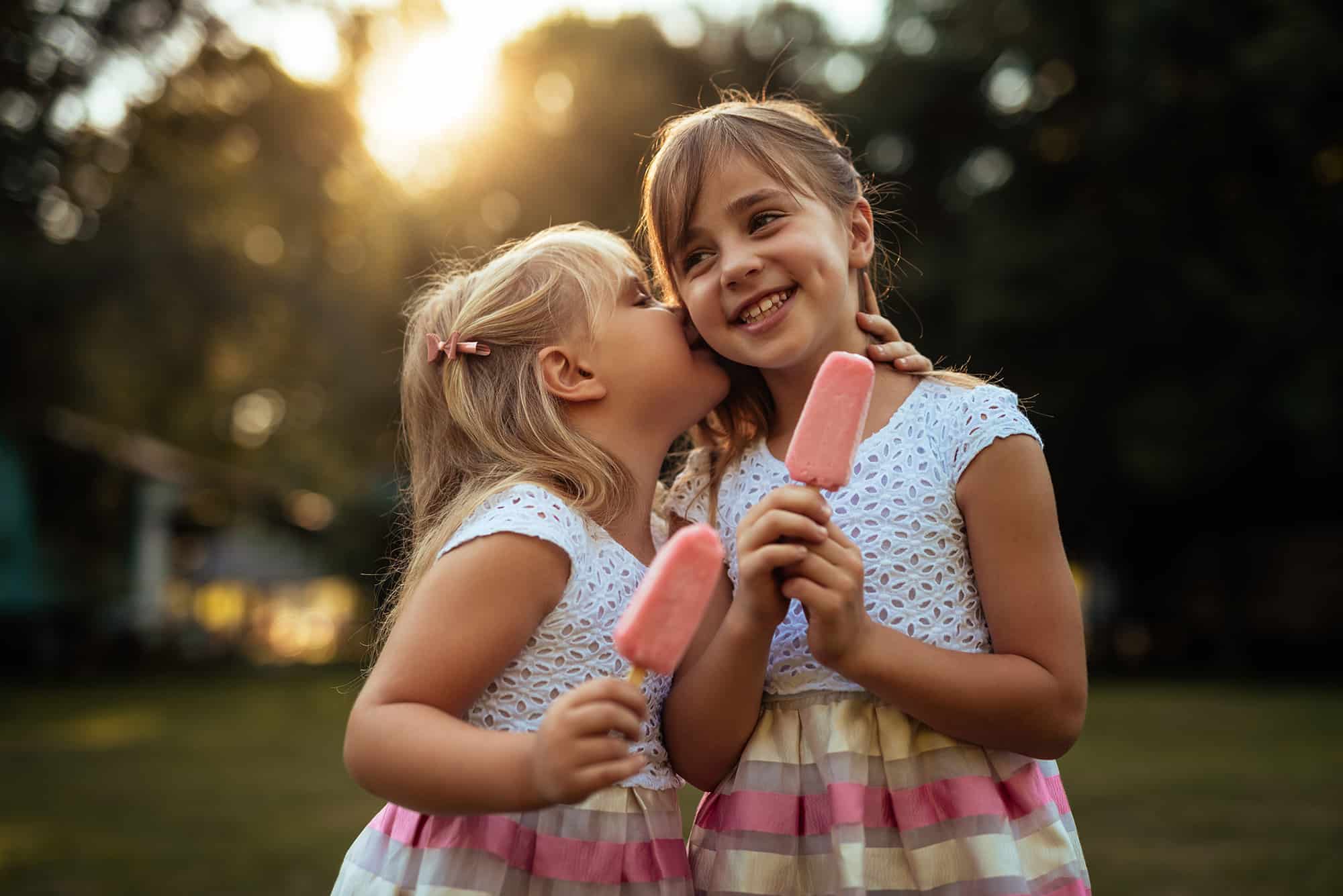 Sisters eating an ice cream while enjoying time together.